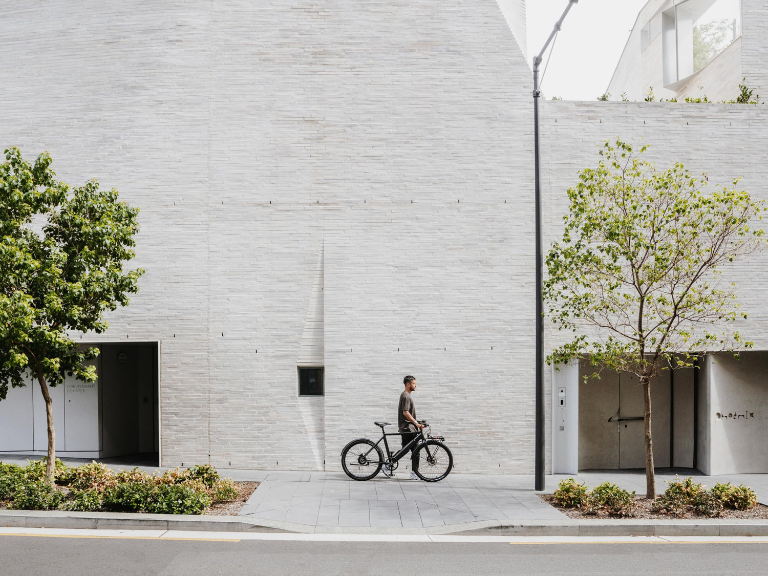 Guy with bike in hands walking through city
