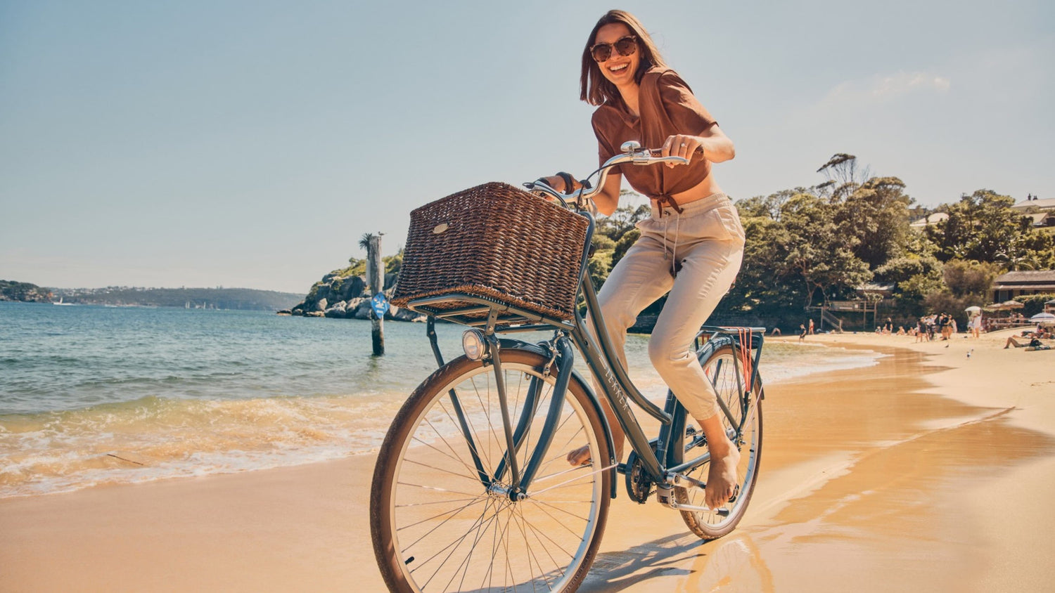 Happy woman biking on beach with denim blue Jordaan 3 speed Lekker Bike Happy woman biking on beach with denim blue Jordaan 3 speed Lekker Bike